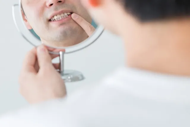 鏡で自分の歯をみる男性